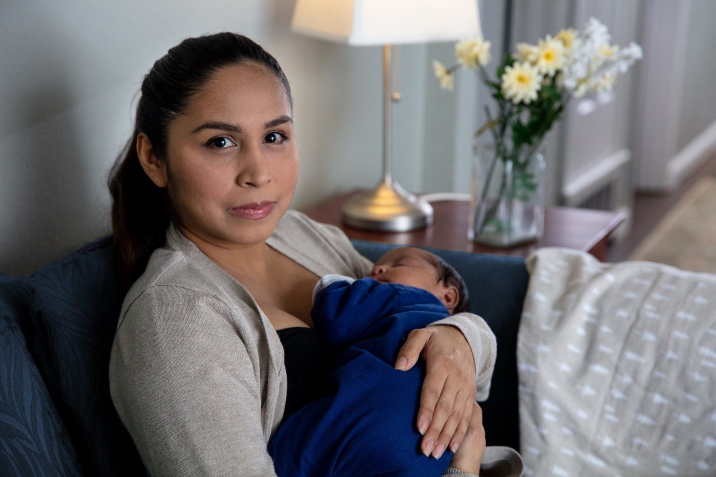 A woman sitting and gently holding a baby in her arms.